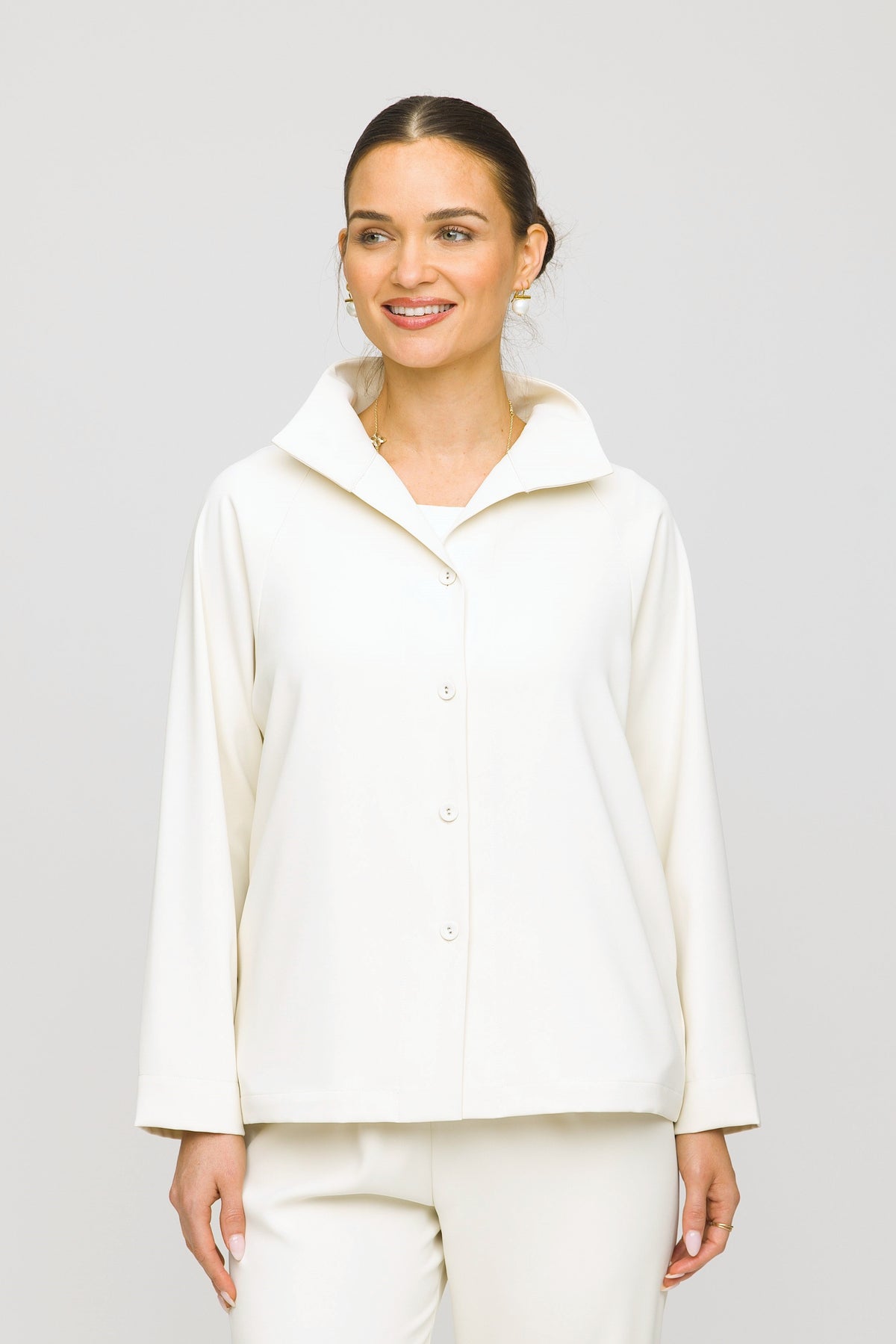 Woman wearing a white jacket and pants against a plain background